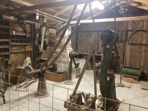 A vintage workshop filled with old machinery and tools, featuring wooden walls and a rustic atmosphere.