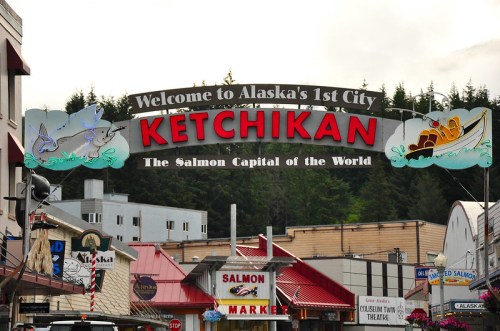 Welcome sign for Ketchikan, Alaska, featuring "The Salmon Capital of the World" with colorful graphics and a forest backdrop.