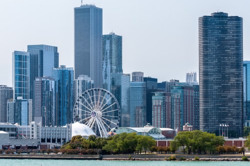 A skyline view of Chicago featuring tall buildings and a Ferris wheel near the waterfront.