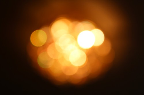 A blurred image of warm, glowing lights creating a bokeh effect in shades of orange and yellow.