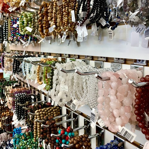 A colorful display of various beads and bracelets hanging on hooks, showcasing different materials and styles.