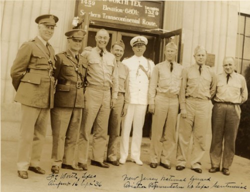 A group of eight military personnel in uniform, posing outside a building, labeled with names and date from 1936.