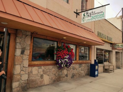 Exterior of Rocky Mountain Seafood restaurant, featuring a stone facade, hanging flower basket, and a sign above the entrance.