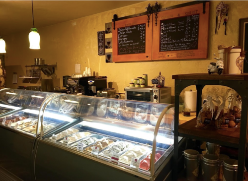 A cozy ice cream shop interior featuring glass display cases filled with various ice cream flavors and toppings.