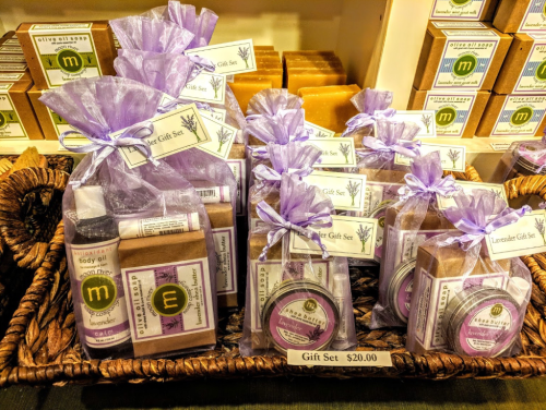 A display of gift sets featuring assorted soaps and body oils, wrapped in purple organza bags, priced at $20.00.