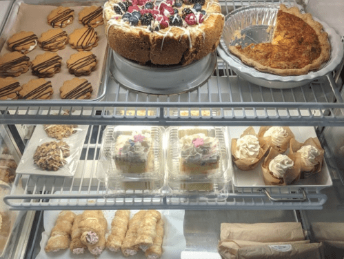A display case filled with various desserts: cookies, cakes, pie, and pastries, all beautifully arranged.