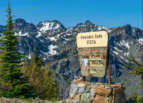 Sign for Heavens Gate Vista at Hells Canyon National Recreation Area, with mountains and clear blue sky in the background.