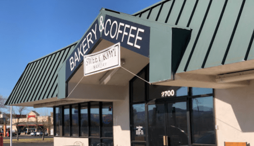 Exterior of a bakery and coffee shop with a green roof and sign reading "Sweet Knot Bakery." Address: 2700.