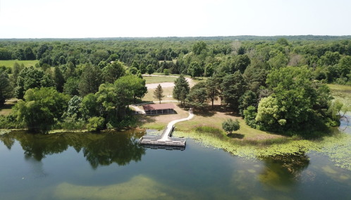 Aerial view of a serene lake surrounded by lush greenery and a small dock extending into the water.
