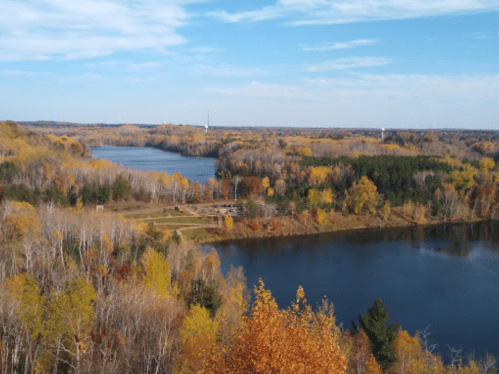 A scenic view of a river surrounded by vibrant autumn foliage and clear blue skies.