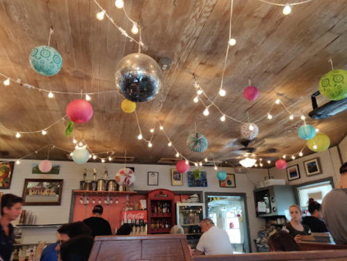 A cozy café interior with colorful paper lanterns and string lights hanging from the ceiling, creating a festive atmosphere.