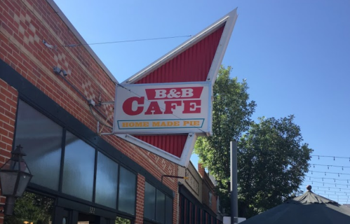 Sign for B&B Café featuring "Home Made Pie," with a retro design and a brick building backdrop.