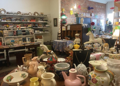 A cozy vintage shop filled with books, decorative items, and colorful pottery on display.