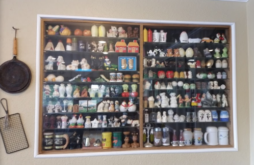 A display case filled with various collectible figurines and items, including animals, dolls, and decorative pieces.