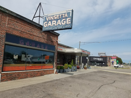 Exterior of Vinsetta Garage, a custom restaurant, featuring a vintage sign and large windows on a sunny day.