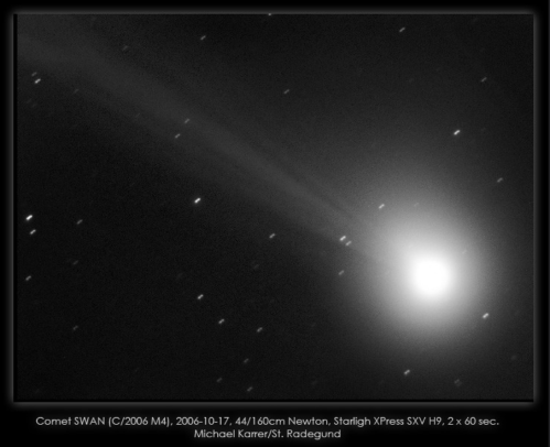 A black and white image of Comet SWAN (C/2006 M4) with a bright nucleus and a long tail against a starry background.