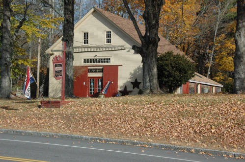 A quaint, two-story building with a red and white exterior, surrounded by autumn leaves and trees.