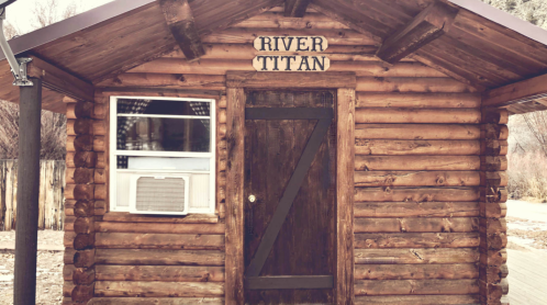 Log cabin with a sign reading "River Titan" above the door and a window on the side.