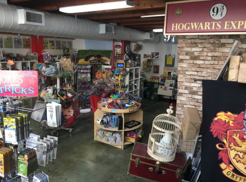 A whimsical shop filled with colorful merchandise, toys, and Harry Potter-themed items, featuring a Hogwarts Express sign.