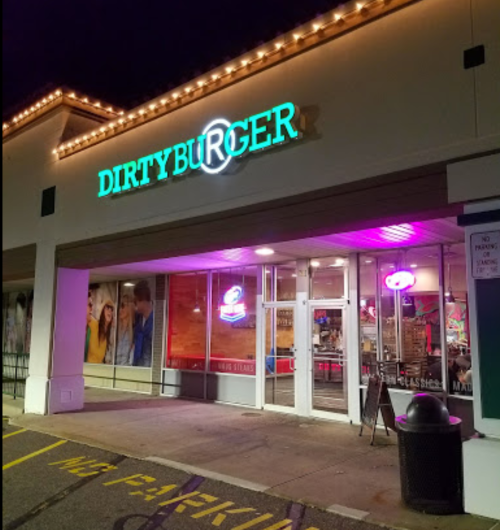 A brightly lit restaurant sign reads "DIRTY BURGER" at night, with colorful neon lights and a modern storefront.