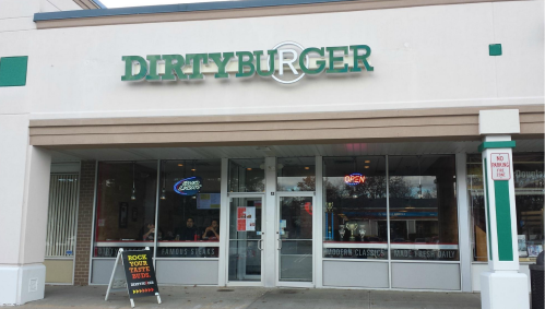 Exterior of Dirty Burger restaurant with large windows, a sign reading "OPEN," and a colorful menu board outside.