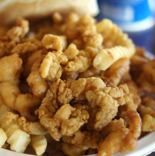 A close-up of crispy fried chicken pieces served with golden French fries.