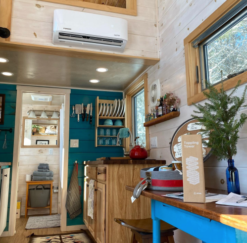 Cozy tiny home interior featuring a kitchen with wooden cabinets, colorful decor, and a dining table.