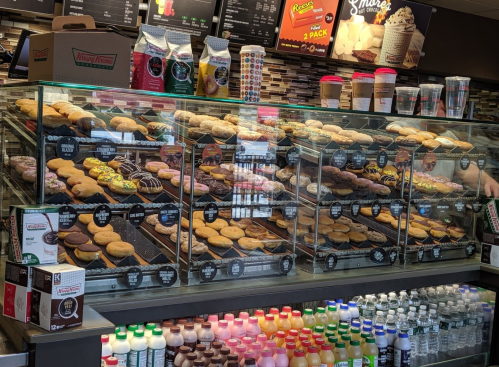 A display case filled with a variety of donuts, including glazed, chocolate, and decorated options, at a donut shop.
