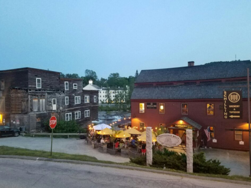 A quaint street scene at dusk featuring a restaurant with outdoor seating and historic buildings nearby.