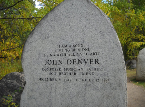A stone memorial for John Denver with an inscription about his life and legacy as a composer and musician.