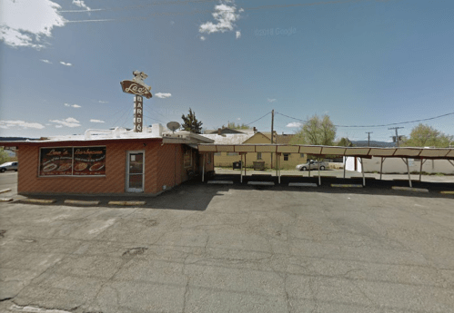A brick building with a sign reading "Lee's Barbecue," featuring a covered outdoor area and clear blue sky.