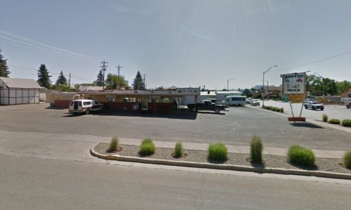 A roadside diner with a large sign, surrounded by a parking lot and sparse landscaping.