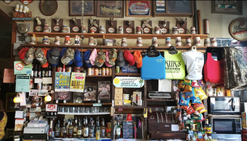 A colorful bar display featuring hats, shirts, trophies, and various bottles on shelves and a counter.