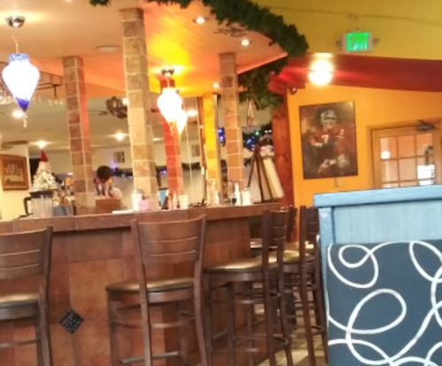 Interior of a restaurant featuring a bar, festive decorations, and a framed picture on the wall.