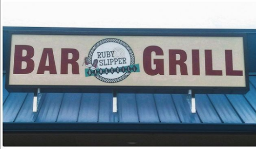Sign for Ruby Slipper Bar & Grill, featuring bold red letters on a light background.
