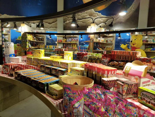 A colorful candy store display filled with various snacks and sweets, featuring bright packaging and a playful atmosphere.