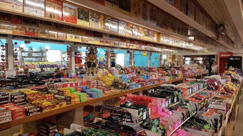 A colorful candy store filled with various sweets and snacks, displayed on shelves and counters.