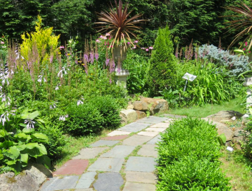 A lush garden path lined with vibrant flowers and greenery, leading through a serene landscape.