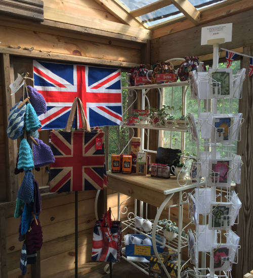A cozy shop interior featuring British-themed items, including a flag, bags, tea, and greeting cards.