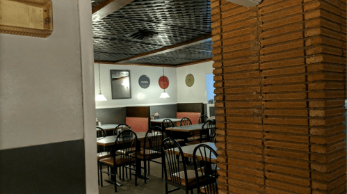 A view of a restaurant interior with empty tables, brick walls, and decorative wall art.