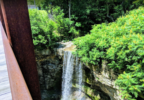 A serene waterfall cascading over rocky cliffs, surrounded by lush green foliage and trees.