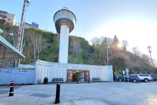 Oregon City Municipal Elevator entrance with a tall tower, surrounded by greenery and a clear blue sky.