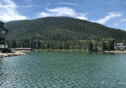 A serene lake surrounded by lush green mountains under a clear blue sky.