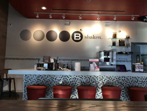 A modern café interior featuring a counter with stools, a menu board, and a minimalist design.
