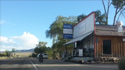A roadside view of a rustic building with signs for a restaurant and motel, surrounded by trees and open landscape.