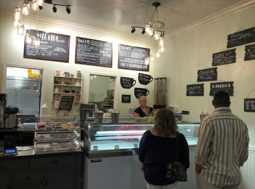 A cozy ice cream shop with a menu board, a display case, and customers ordering at the counter.
