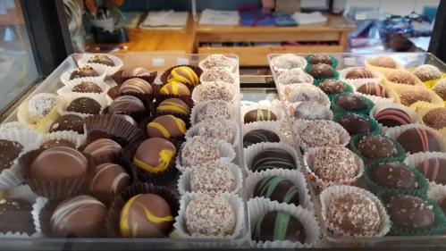 A display of assorted chocolate truffles in various flavors and designs, arranged in paper cups.