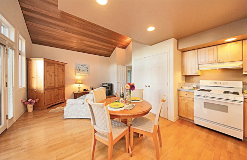 Cozy dining area with a round table, chairs, and a kitchen in a bright, open living space with wooden accents.