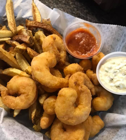 A serving of golden fried shrimp with a side of crispy fries, accompanied by two dipping sauces in small cups.