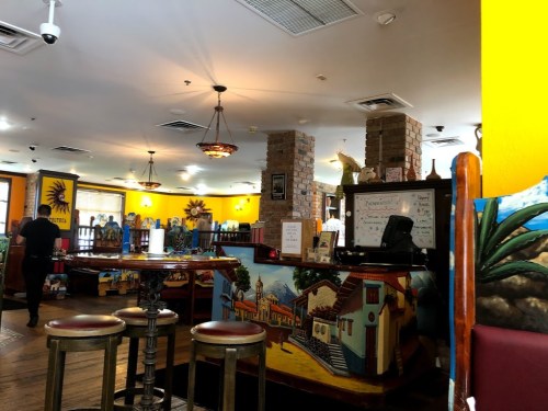 A vibrant restaurant interior with colorful murals, wooden tables, and a cozy atmosphere.